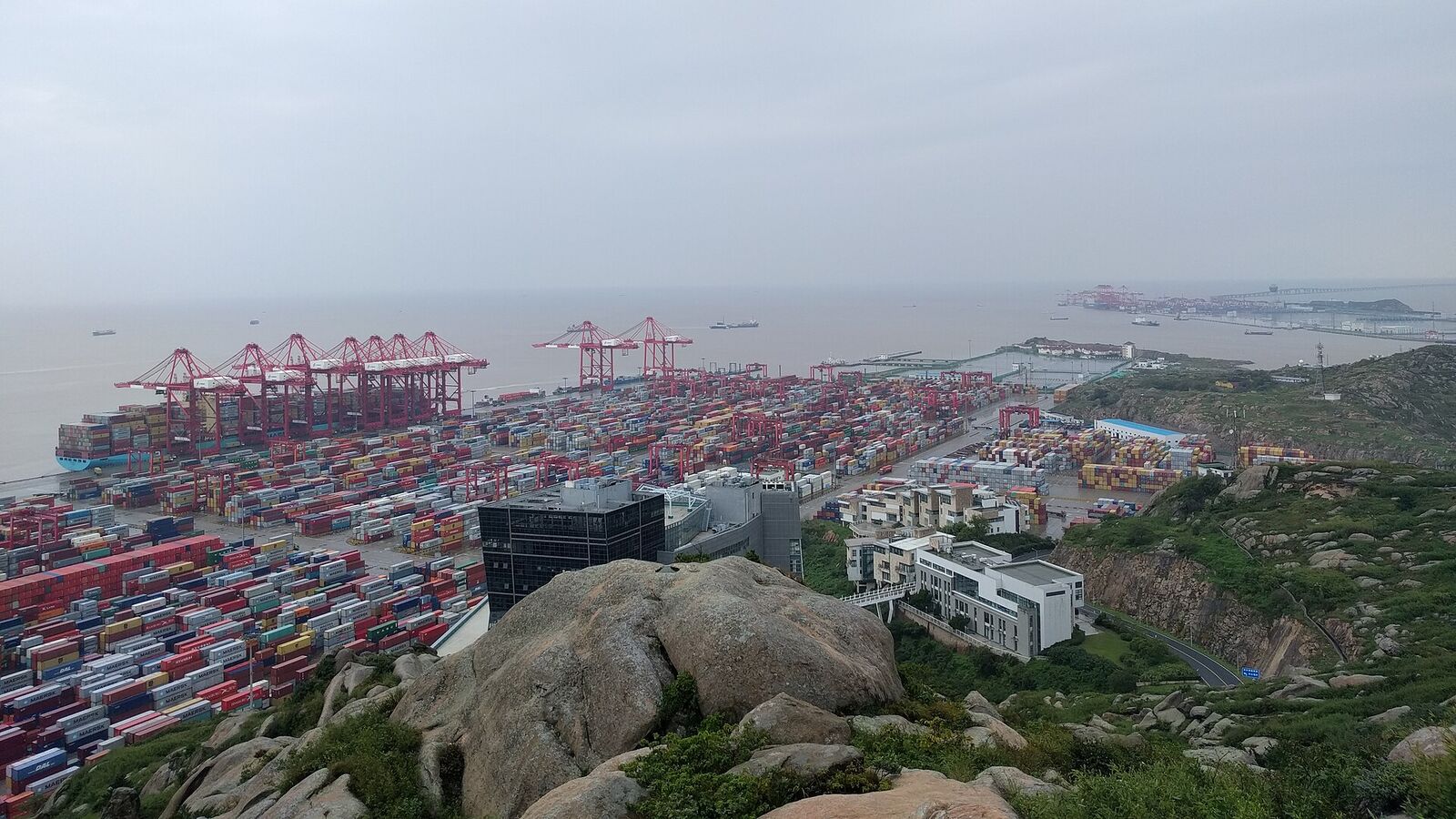 Containerhamnen Yangshan utanför Shanghai, med kranar och staplade containrar vid havet
